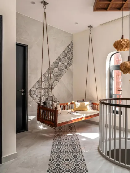 In this first-floor living area, I used patterned floor tiles to create a visual pathway leading to a traditional wooden swing. The tiles extend up the wall, creating a unique and artistic feature that blends modern and traditional styles.