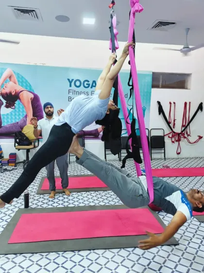 A closer look at a partner aerial pose, with me observing to ensure safety and proper form. The hammock supports both students, allowing them to create a shape that would be impossible on the mat alone.