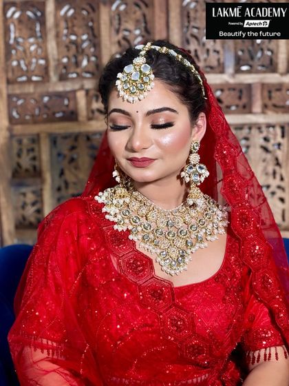 Another angle of the quintessential red bridal look, focusing on the flawless base and contouring. Students learn to sculpt the face to enhance features, ensuring the bride looks stunning in photos and in person.