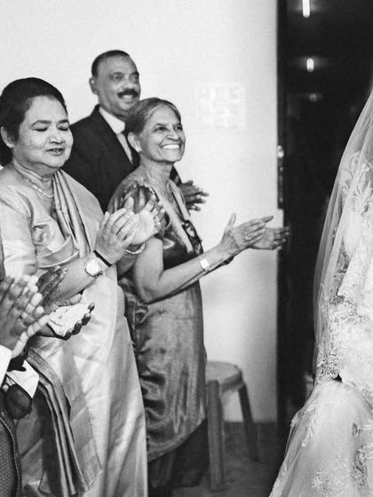 The bride's family applauds as they see her for the first time in her wedding dress. A beautiful, candid moment of joy and pride.