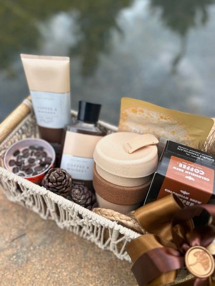 A coffee-lover's dream hamper in a macrame basket. This Rakhi gift is filled with coffee-scented bath products, gourmet coffee, and a reusable mug.