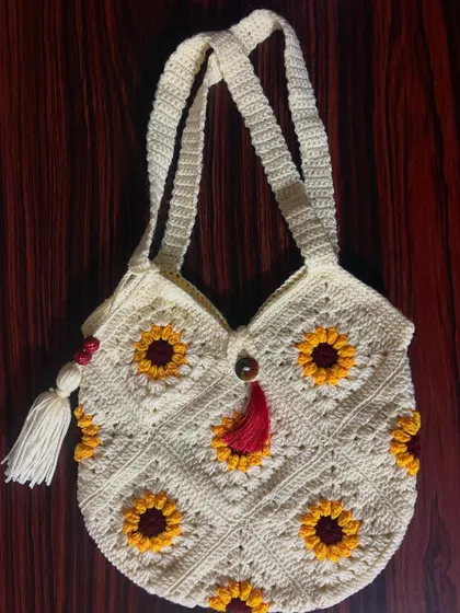 My granny square tote bag, featuring a cheerful sunflower pattern and decorative tassels, is a perfect blend of bohemian style and practical design for everyday use.