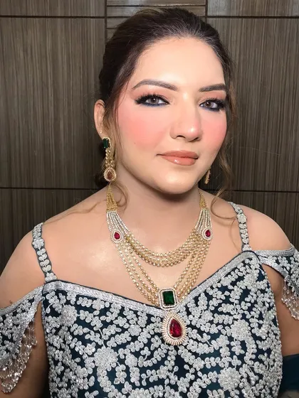 This party look features a stunning layered necklace with emerald and ruby drops, adding a pop of color to her embroidered outfit.