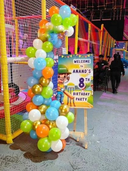 A cricket-themed welcome sign for an 8th birthday party. A custom easel stand with a personalized welcome message is decorated with a colorful balloon garland.