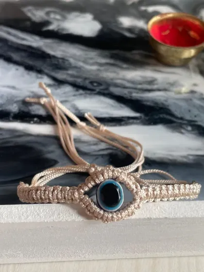 This handcrafted macrame bracelet features a protective evil eye charm. It's a meaningful and stylish piece, perfect as a Rakhi or a friendship band.
