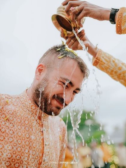 The groom getting a refreshing shower during the Haldi ceremony. The joy on his face is priceless, and these moments add a lot of fun to the wedding film.