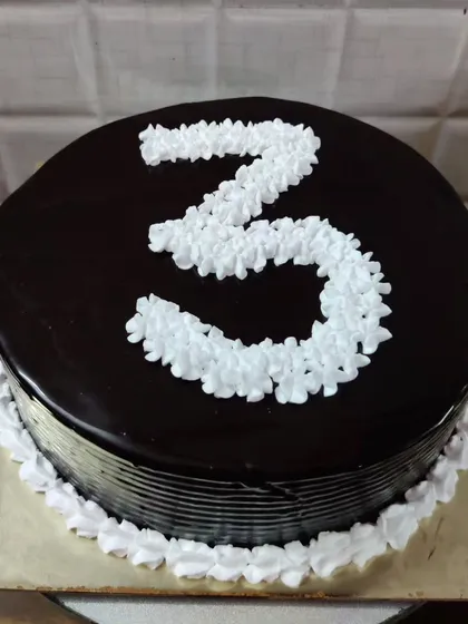 A chocolate number cake, perfect for celebrating a 3rd birthday or anniversary. The number is piped with white buttercream flowers.