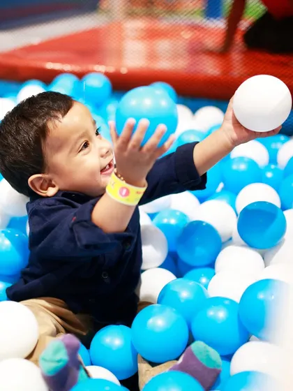 Gentle fun for our littlest visitors. A toddler enjoys the soft and safe environment of our My Burrow ball pit, designed specifically for ages 2 to 4. This area is perfect for sensory play and developing motor skills.
