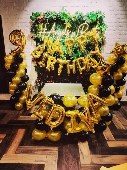 A unique backdrop combining a lush green wall with black and gold balloons. I can spell out any name or message with foil balloons to personalize the decoration for your birthday party.