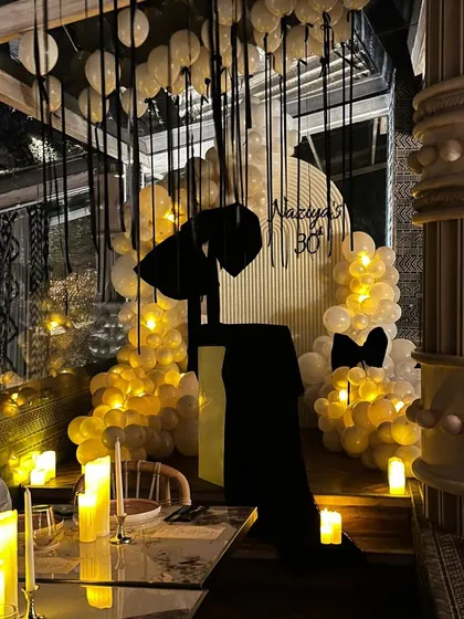 For this chic 30th birthday, we designed a "Bow-tiful" theme with a moody black and white palette. The decor features dramatic black bows, warm candle lighting, and elegant balloon arrangements for a sophisticated and modern milestone party.