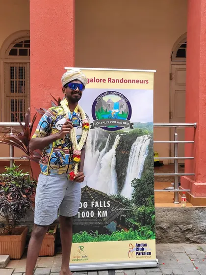 The triumphant finish of the Jog Falls 1000K BRM. A rider celebrates his achievement, finishing 9th among the fastest riders with an impressive time of 64 hours and 56 minutes.
