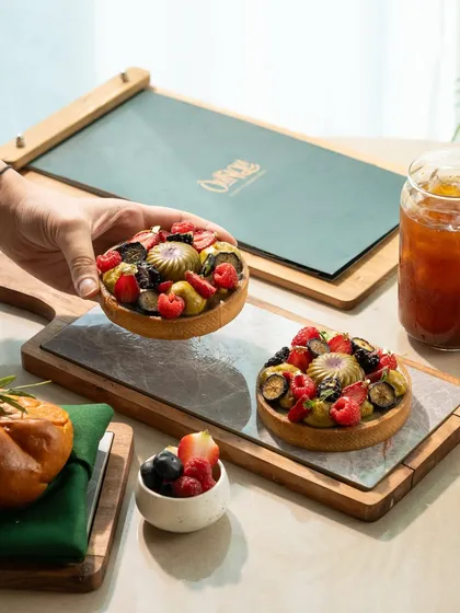 A beautiful fruit tart with fresh berries. The composition with a hand reaching for it makes the shot feel dynamic and interactive.
