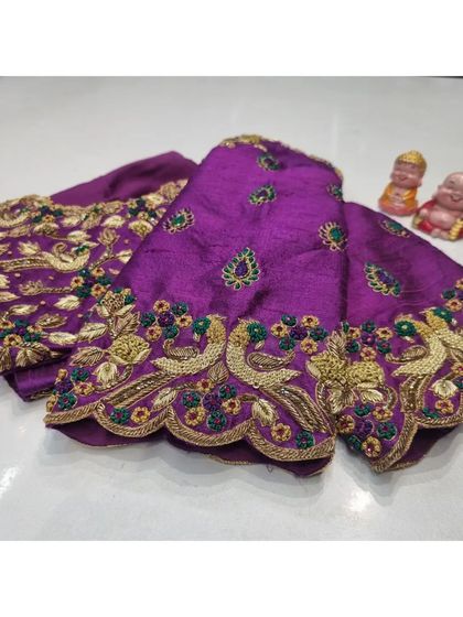 The unstitched sleeves of a purple bridal blouse laid out to display the intricate peacock and floral embroidery. This shows the piece before it's constructed into a final garment.