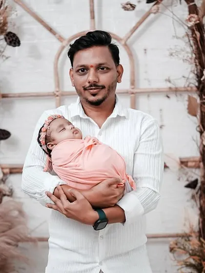 A proud father holds his newborn daughter, wrapped in a soft pink swaddle. This individual portrait is a wonderful part of the complete family session.