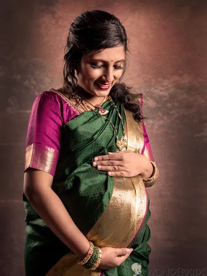 I believe in celebrating motherhood in all its forms. This classic studio portrait of an expecting mother in a beautiful green and pink saree highlights her radiant glow with soft, elegant lighting.