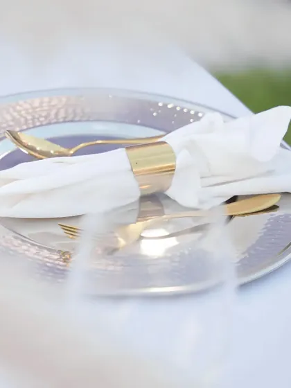 An elegant table setting featuring a hammered silver charger plate and gold-accented cutlery. We believe luxury is in the details, and our sophisticated place settings elevate the dining experience for every guest.