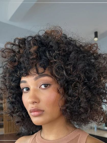 Curls and color are a perfect match. Here, we added subtle lighter pieces to these beautiful curls to enhance their shape and texture, creating a look that is both soft and defined.