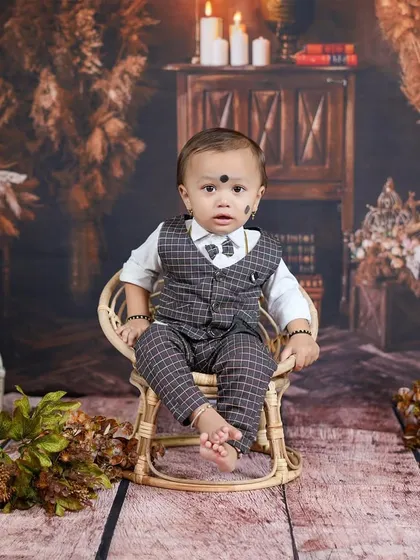 A dapper little gentleman in a three-piece suit, looking sharp against a rustic, vintage-inspired backdrop.