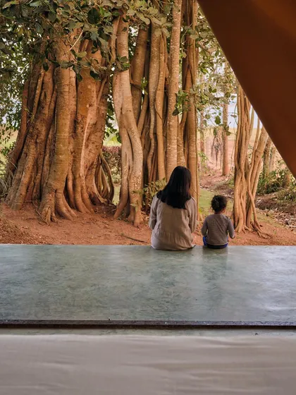 We design spaces that create quiet, memorable moments. At the Fireflies Resort in Kabini, a simple polished concrete plinth extends from a glamping tent, offering an uninterrupted view of an ancient banyan tree, inviting guests to pause and connect with nature.
