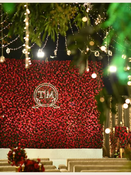 A wall of red roses with a custom monogram is the star of this stage. Framed by twinkling lights, it creates a backdrop that is both incredibly romantic and highly personal.