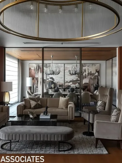 Another view of the living room, showcasing the arrangement of bespoke furniture, including high-back chairs and a plush ottoman, designed for both style and comfort.