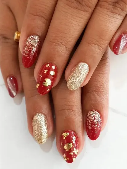 Perfect for celebrations, this festive manicure combines a rich red base with accent nails in full-coverage gold glitter and delicate gold foil flakes. This is a popular choice for bridal parties and holiday events.