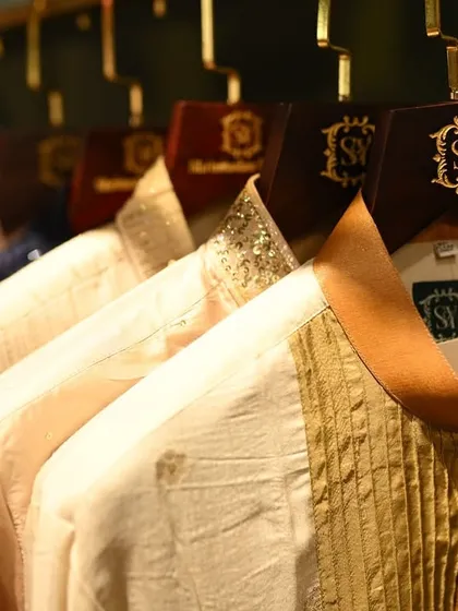 Your style journey connects past traditions to your modern narrative. A close-up of the varied collars and fabrics of our kurtas, from pleated details to shimmering gold.
