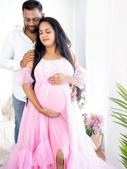 A gentle and loving moment where the partner embraces the mom-to-be, both looking down at the baby bump.