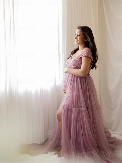This profile shot beautifully highlights the silhouette of her baby bump against the soft light from the studio window.