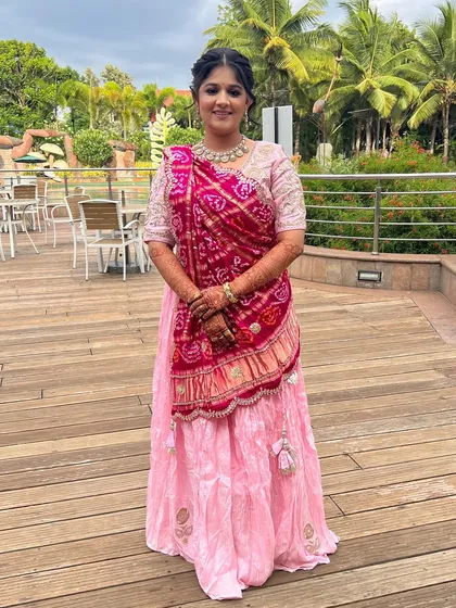 A full-length shot of the bride, showcasing her lovely pink lehenga and traditional draping.