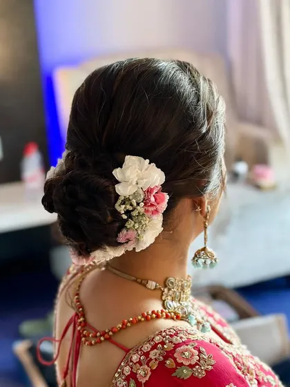 A beautiful bridal bun decorated with a mix of fresh pink and white flowers. This style is perfect for a bride who wants a touch of color in her wedding day hair.