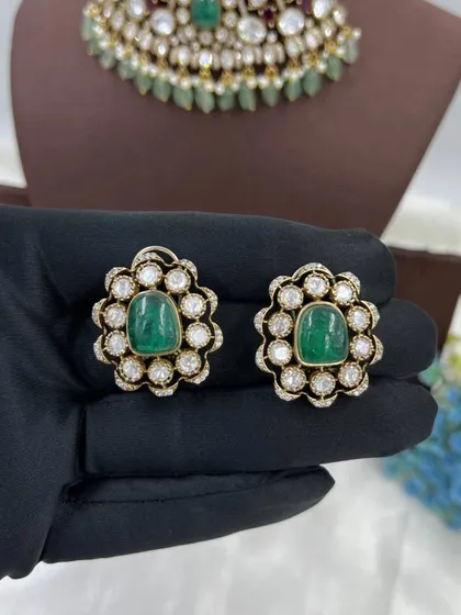 A pair of simple yet elegant polki and emerald stud earrings.