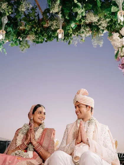 The serene moments just before the pheras begin, with the couple sharing a look of love and anticipation under a canopy of flowers.