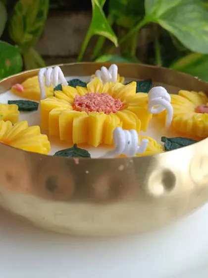 A side view of the sunflower urli candle in its brass bowl.