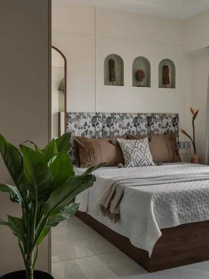 A closer look at the bedroom, focusing on the custom headboard with its unique print and the arched wall niches that display curated decor pieces, adding a personal touch.