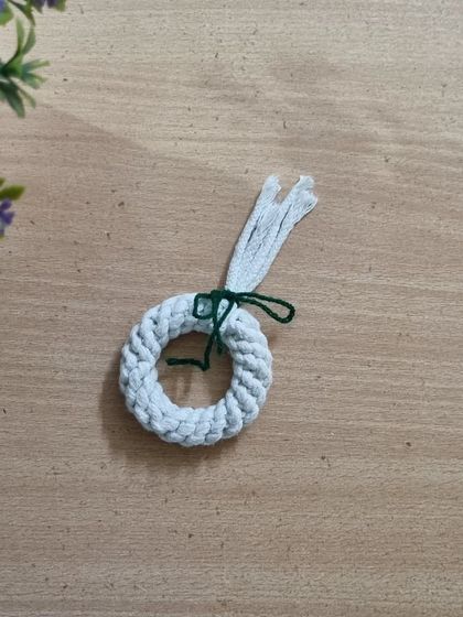 The wreath ornament in progress, showing the basic knotted ring before the final decorative touches are added.
