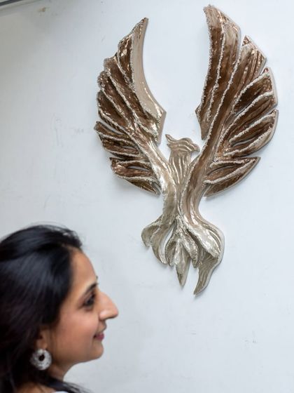 Admiring the finished "Eternal Flight" sculpture. The metallic tones and shimmering details tell a story of honor and progress.