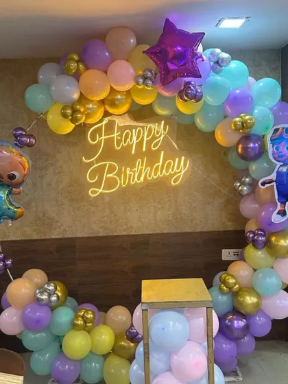 A Cocomelon themed ring backdrop in soft pastel colors. This decoration is perfect for photos, featuring character cutouts and a 'Happy Birthday' neon sign in the center.