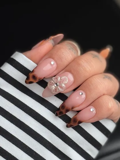 A beautiful combination of textures and patterns. This set features tortoiseshell French tips, a delicate 3D floral accent nail with a gem center, and scattered rhinestones for a sophisticated finish.