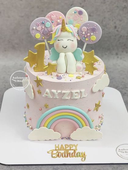 A magical unicorn cake with a lemon blueberry flavor. This cake features a cute unicorn, a rainbow, clouds, and balloon-like lollipops, perfect for a first birthday.