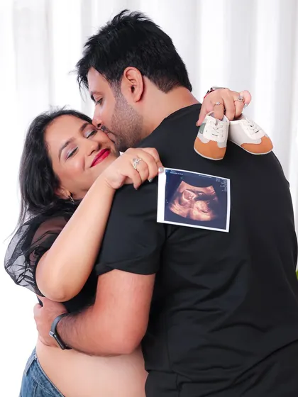 This intimate photo shows the couple embracing, with the ultrasound photo and baby shoes telling the story of their growing family.