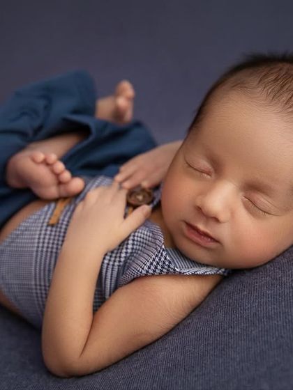A close up capturing a sweet, sleepy expression from the baby boy in his stylish outfit.
