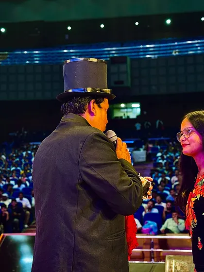 A close-up shot of me interacting with a volunteer on stage in a large auditorium. Even in a big venue, I make sure to create personal and engaging moments.