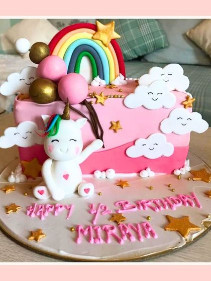 A cheerful half-birthday cake featuring a cute unicorn, a rainbow, and happy clouds.