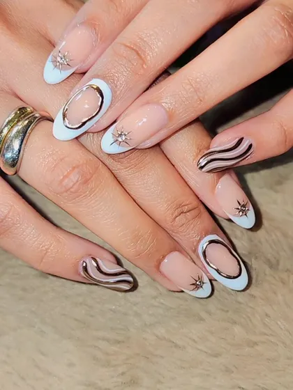 A modern and abstract design. This set combines a negative space look with light blue tips, chrome silver swirls, and 3D starburst accents for a unique, edgy style.