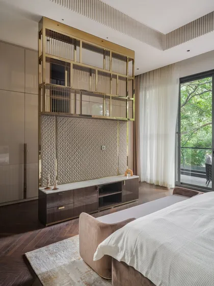 This view shows the custom TV and storage unit we designed for the bedroom. The unit features a textured backdrop, open shelving with a brass frame, and closed cabinets, blending functionality with high-end design.