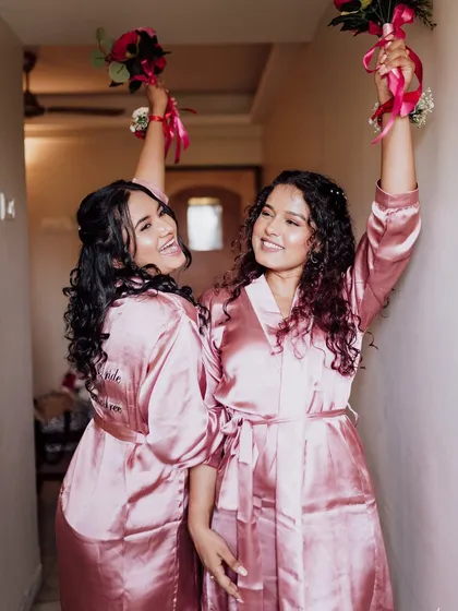 A fun and joyful shot of two bridesmaids in their matching robes, getting ready for the big day.