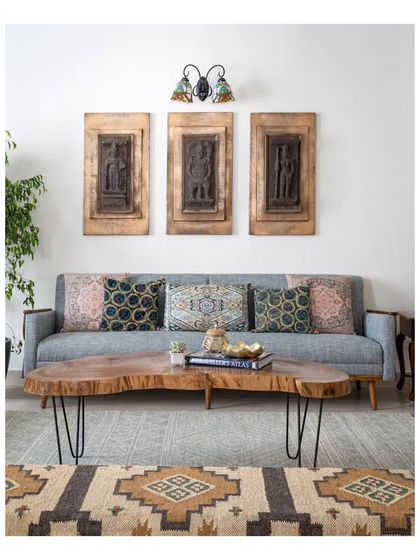 A detail of the living room seating, with a live-edge sandalwood center table and a sofa adorned with wooden idols. The design intuitively blends the rustic feel of Spanish and Indian decor.