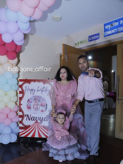 The birthday girl and her family posing in front of their circus-themed party entrance.