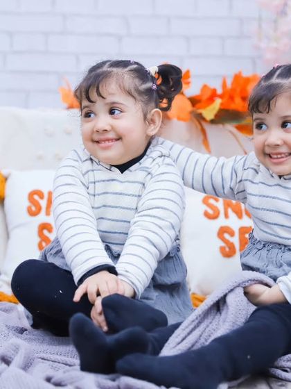 Two sisters sharing a blanket and a smile. These cozy, candid moments are what our photography is all about.
